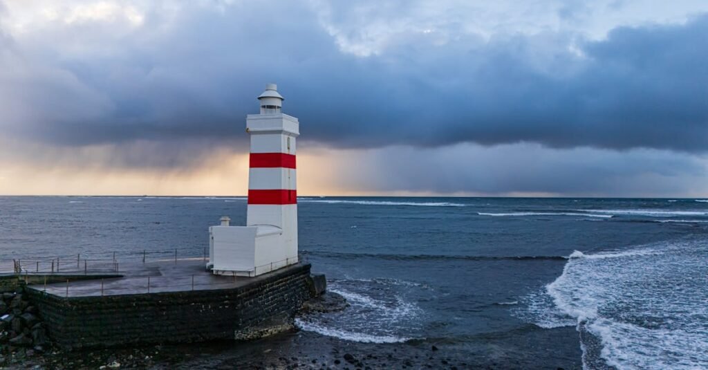 A stunning view of the Garðskagaviti Lighthouse against the dramatic ocean backdrop in Iceland.