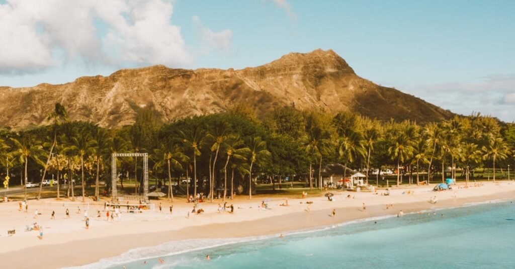 A scenic view of Diamond Head with a sunny beach and clear blue waters in Hawaii.