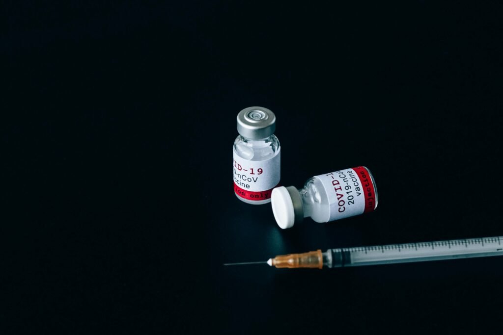 Two COVID-19 vaccine vials and syringe on dark backdrop symbolizing vaccination and healthcare.