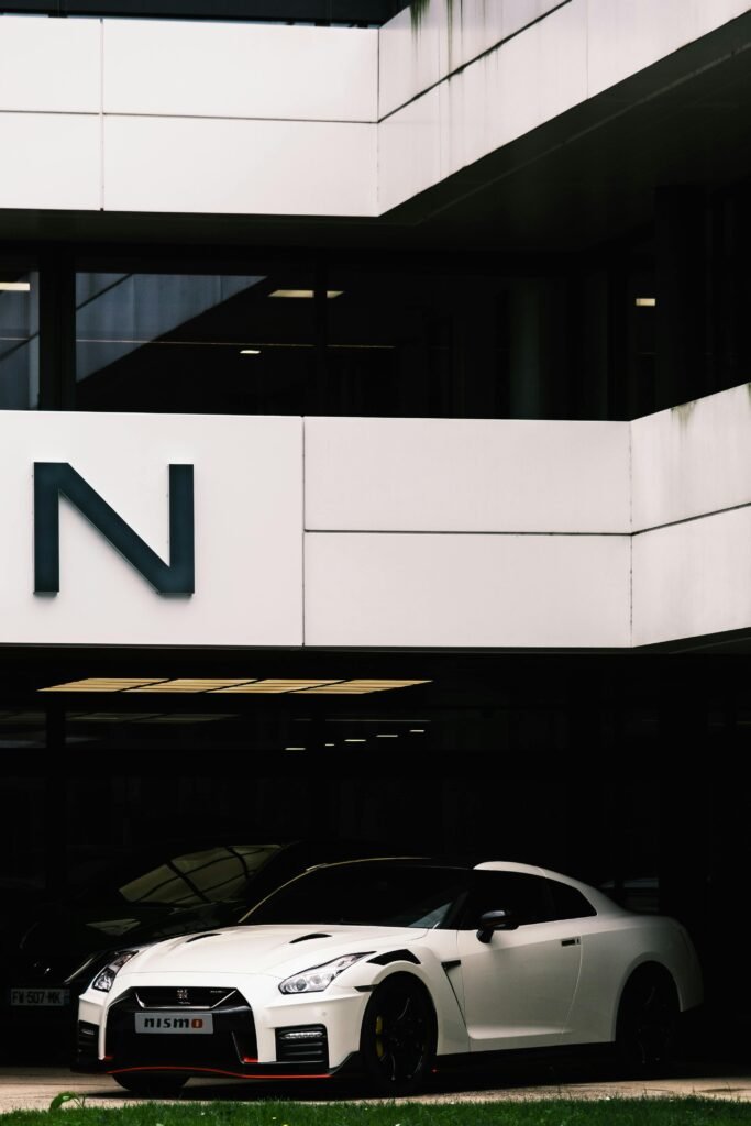White Nissan GT-R NISMO parked under building overhang, showcasing modern car design.